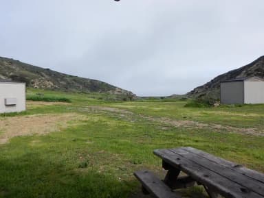 View of wide canyon with picnic table and green grass in foreground.