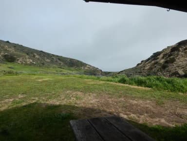 View of wide canyon with picnic table and green grass in foreground.