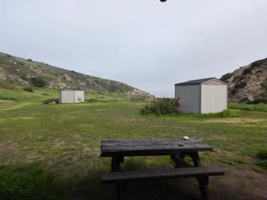 View of wide canyon with picnic table and green grass in foreground.