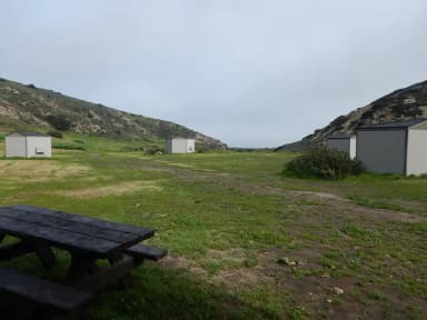 View of wide canyon with picnic table and green grass in foreground.
