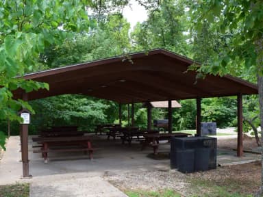 Showing shelter, picnic tables,grill and trash receptacle.
