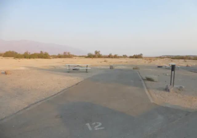 Standard Non-electric Campsite #12 with picnic table, fire ring, and paved parking pad at Furnace Creek Campground.