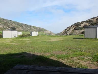 View of wide canyon with picnic table and green grass in foreground.