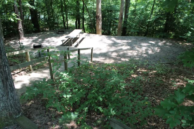 Gravel site with table, grill, fire pit with steps leading down from parking