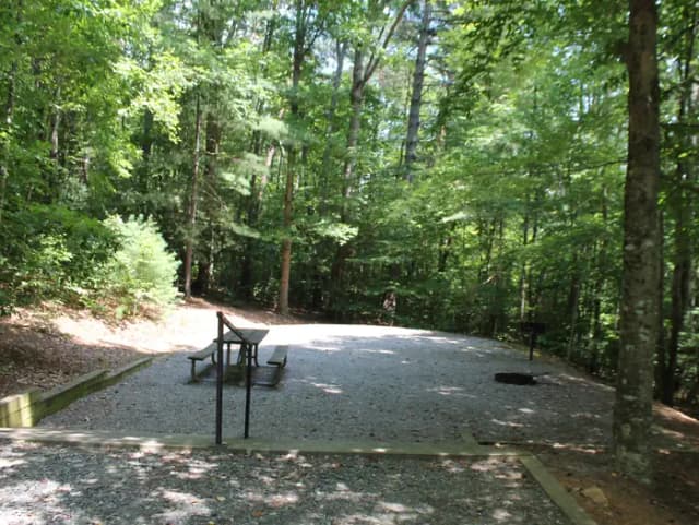 Gravel site with table, grill, fire pit with steps leading down from parking