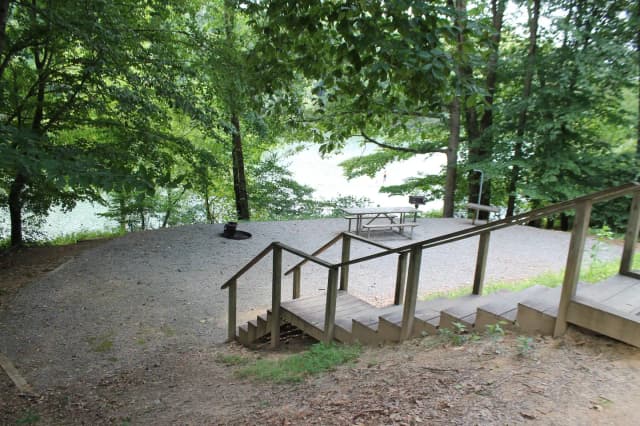 Steps leading down to gravel site with fire pit, table, grill
