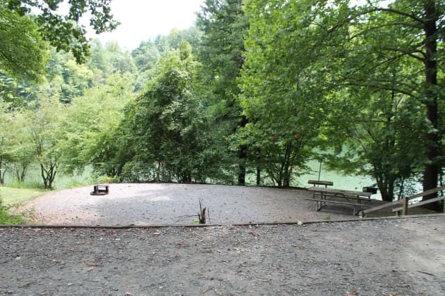 Steps leading down to gravel site with fire pit, table, grill