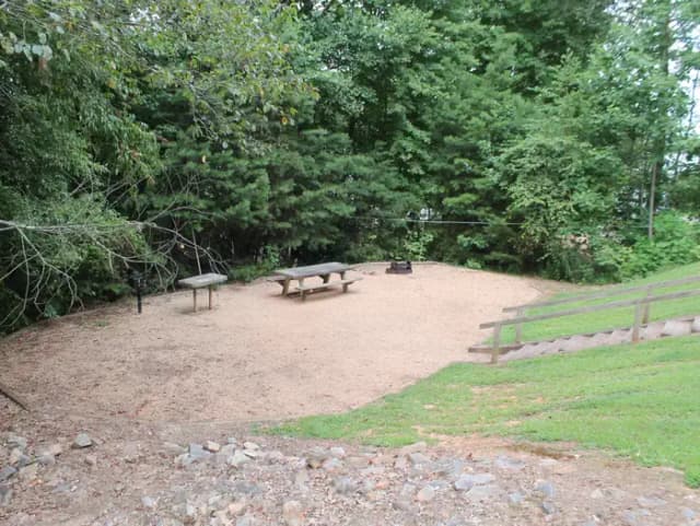 Gravel site with table, fire pit, grill surrounded by trees