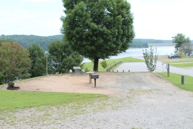 Gravel site with fire pit, table, grill, and views of the lake