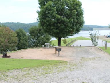 Gravel pull in to site with large tree and views of the lake