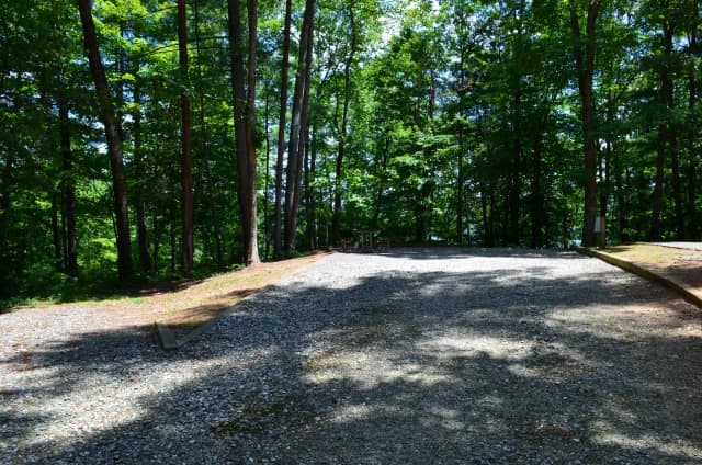 Gravel site with fire pit, grill, table, with dense tree coverage
