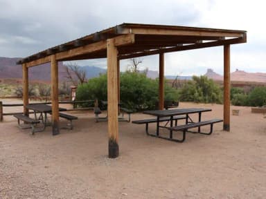 Close up of the Lower Onion Creek Group Site A shade shelter with picnic tables underneath. The Castelton rock feature can be seen in the distance, lining the horizon.
