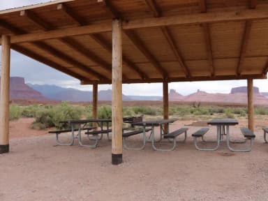 Close up of the Lower Onion Creek Group Site B shade shelter and picnic tables. Castleton and the La Sal Mountains can be seen in the distance.