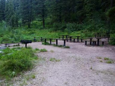 Picnic tables and benches near the raised grill and in-ground fire pit.