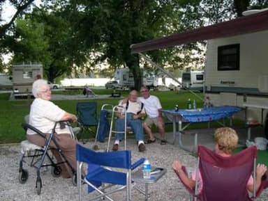 Senior campers using chair assistance and visiting at campsite.