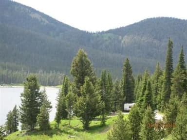 Pine trees, mountains & campsite with camper