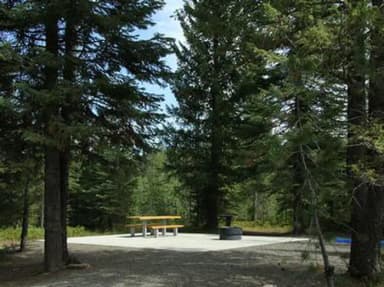 Accessible site with paved common area round fire pit, with picnic table.