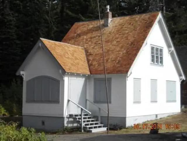 Sunlit white cabin with shutters closed, gray trim and six steps up.