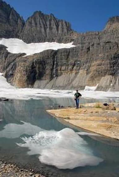 A man views rock cliffs above an alpine lake near Many Glacier