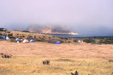 Tents and 5-foot tall windbreaks perched on an ocean bluff overlooking an islet covered in fog., filed by the agency against 9 campsites at San Miguel Island