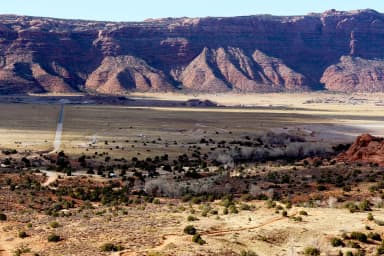 Overview of Ken's Lake Campground with red rock cliffs lining the horizon., filed by the agency against 48 campsites at Ken's Lake Campground